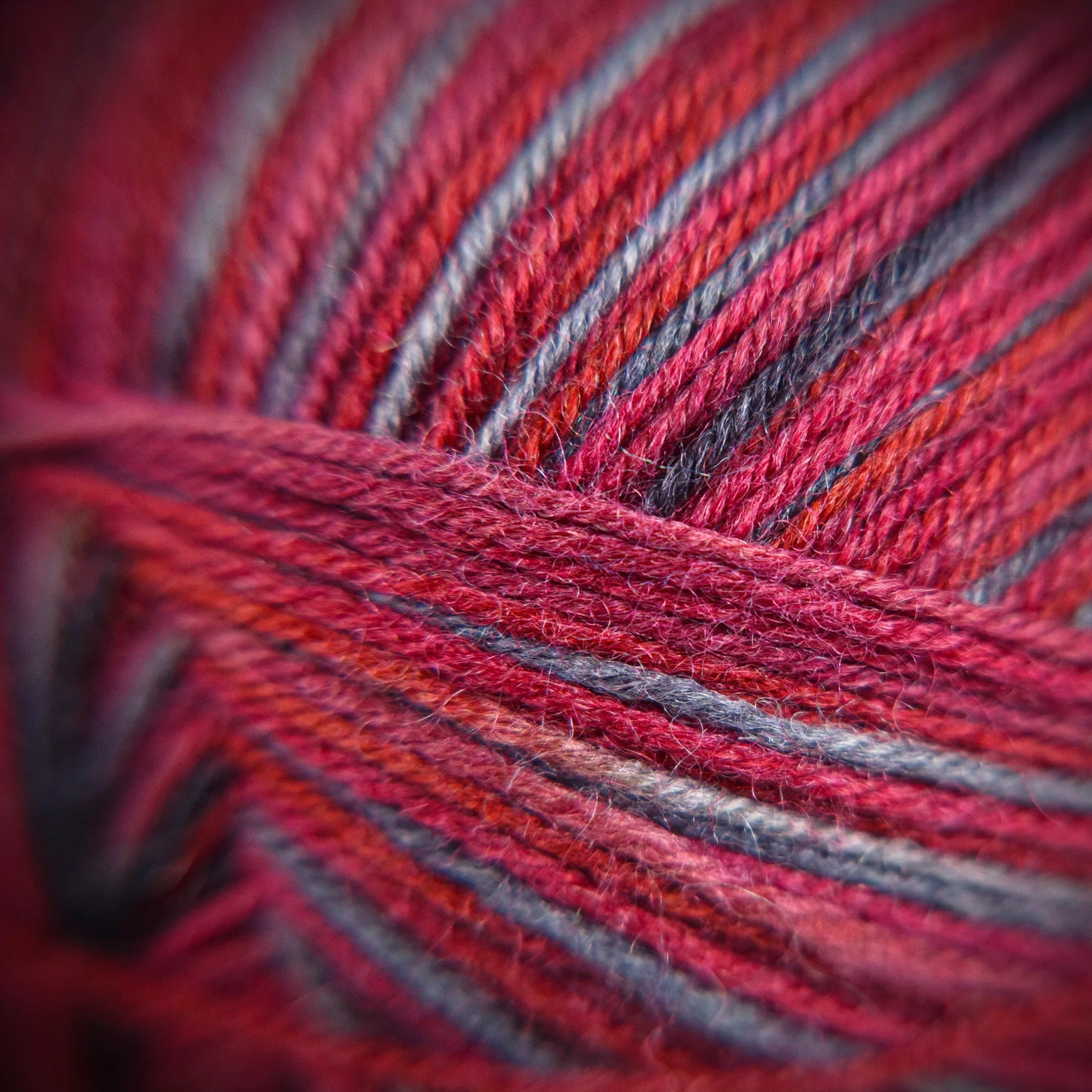 Fibre-level close-up of Roasted Fig yarn, showing twist detail and variegated mulberry, wine, and violet tones.