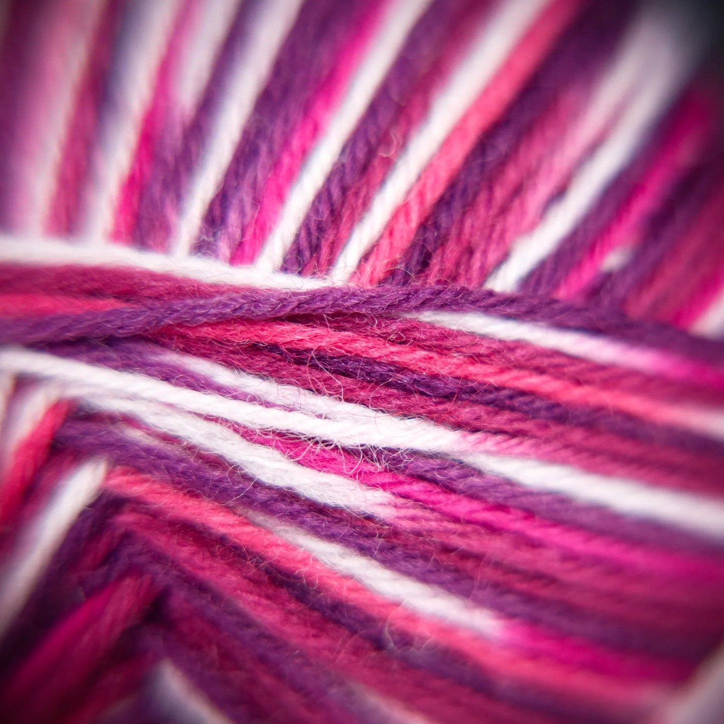 Macro photo of Sock Flock ‘Raspberry Ripple’ yarn in vibrant raspberry and pastel blue twist.