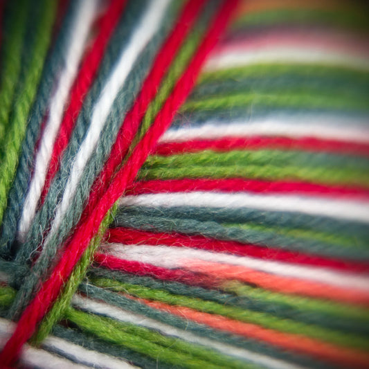 Macro detail of Sock Flock ‘Apple Gala’ yarn strands, combining soft green, cherry red and cream.
