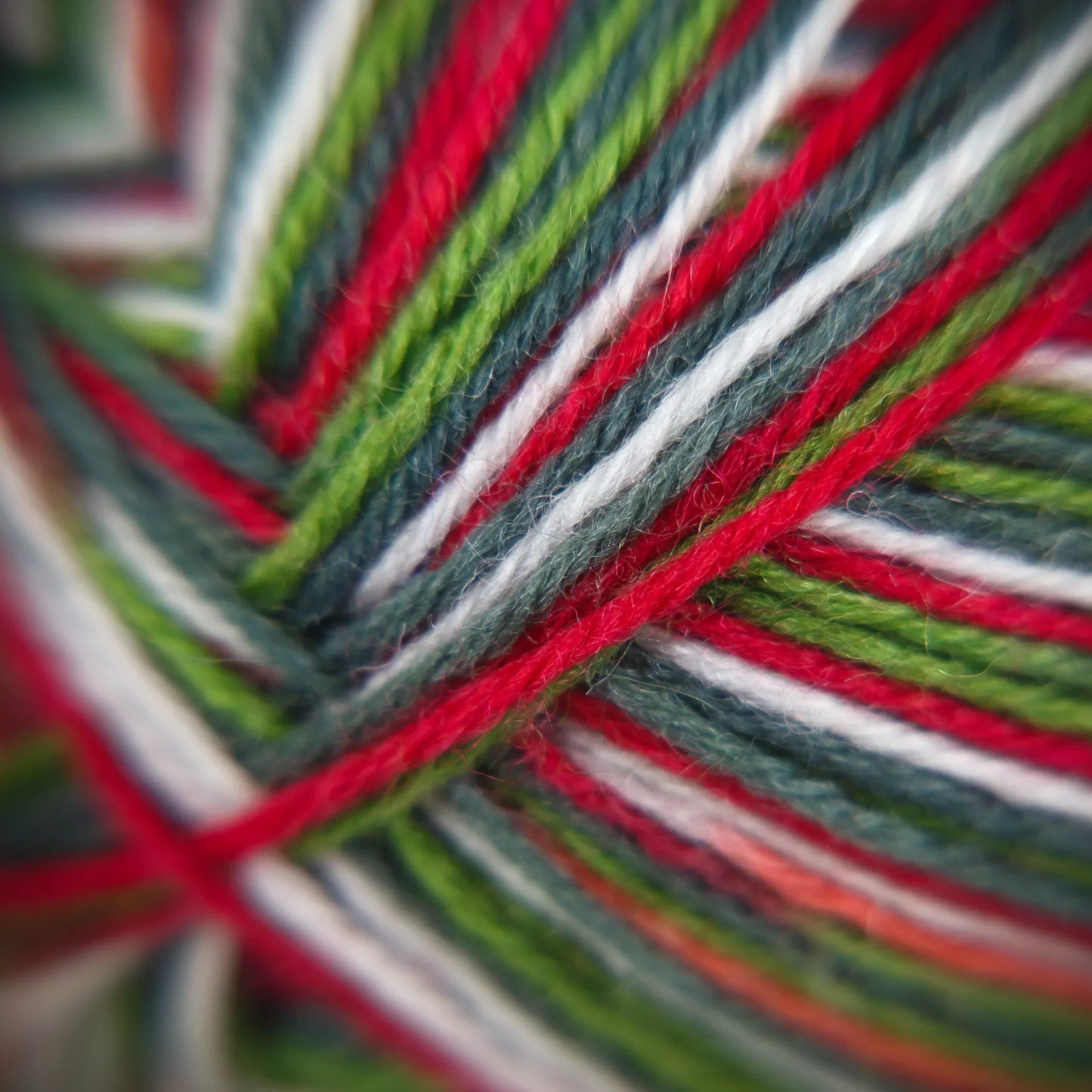 Close-up of Apple Gala yarn, capturing bright green, red and white strands under diffuse lighting.