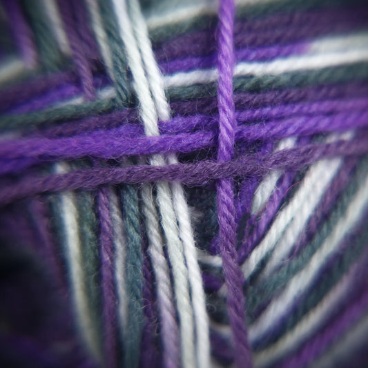 Macro of Purple Ivy yarn showing base tones of black-violet with warm berry layers and soft twist.