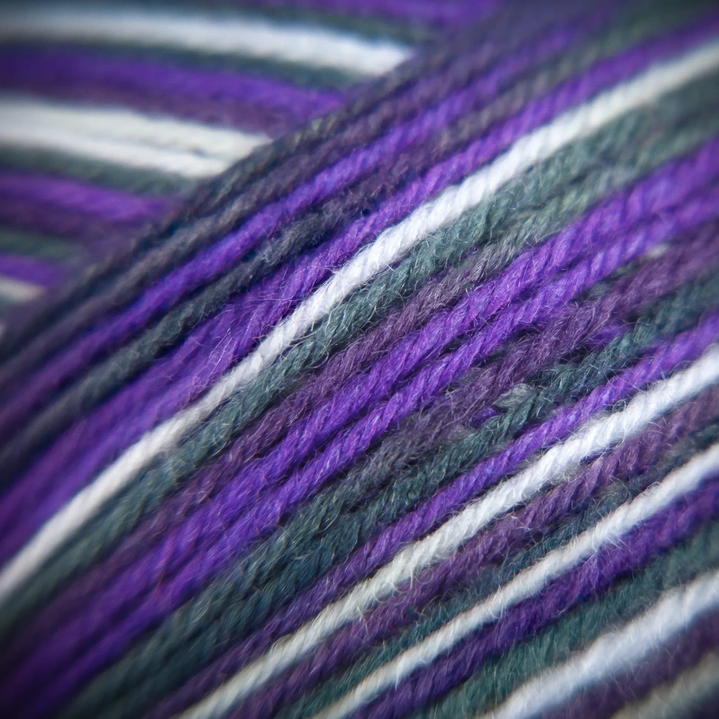 Macro image of Purple Ivy yarn, revealing gradient tones between mulberry, soot, and soft grape.