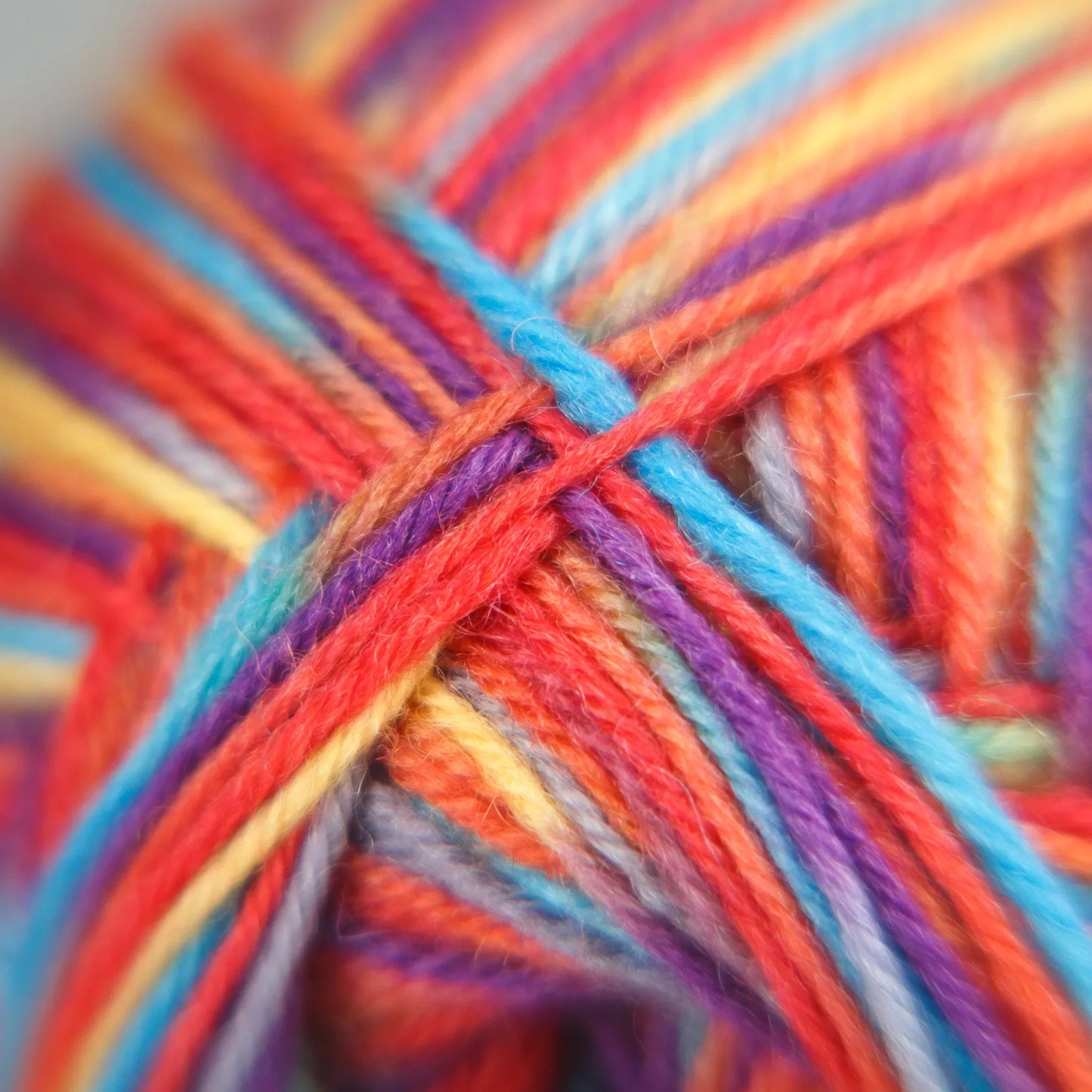 Fibre macro photo showing Rainbow Reef colourway's sunset pinks, seafoam and sun-washed yellow strands.