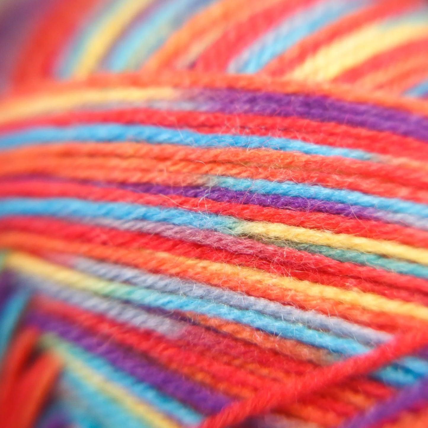 Macro view of Rainbow Reef yarn in variegated tones, showing balanced strand blending and soft texture.