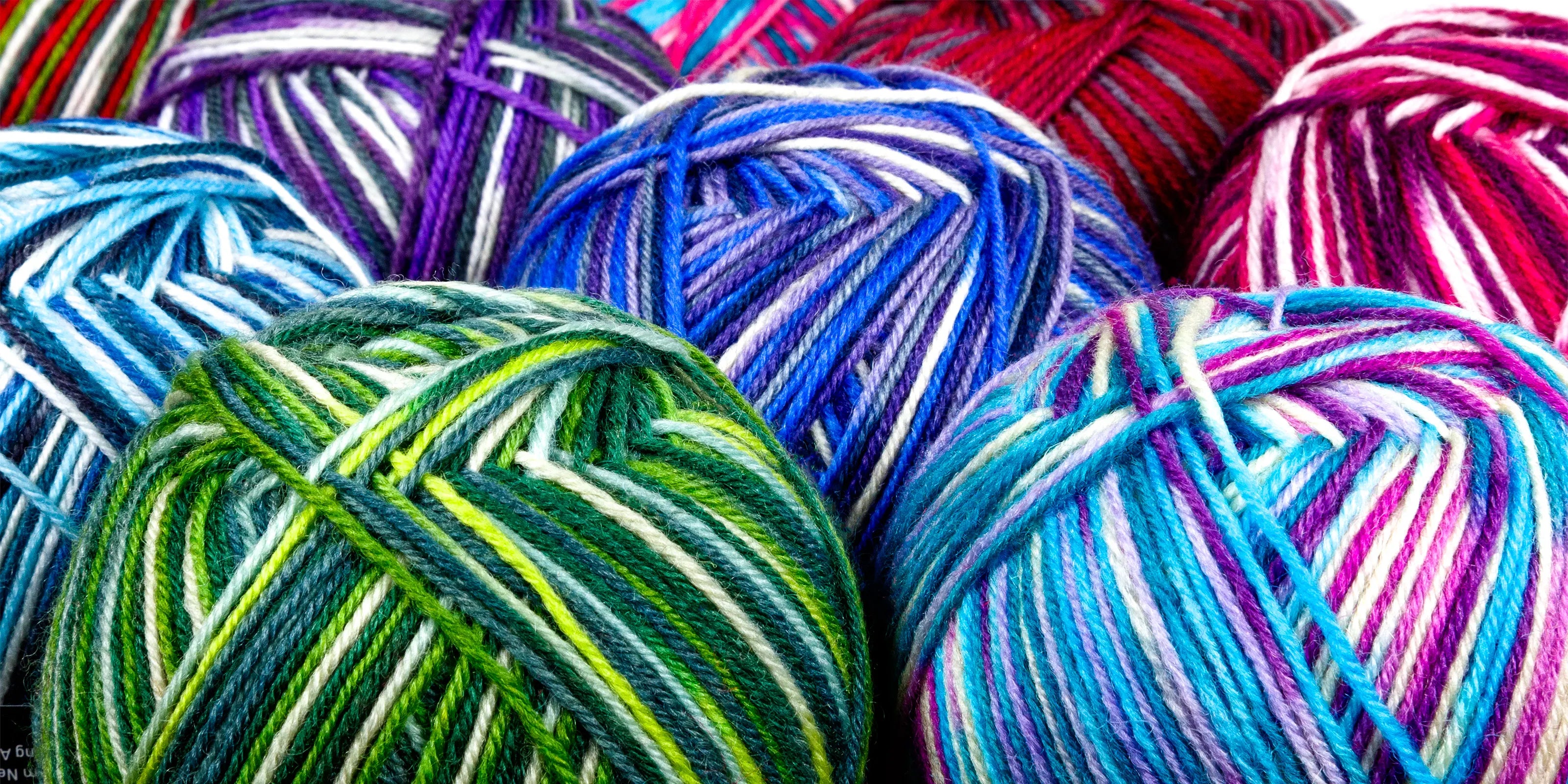 Close-up banner image of Sock Flock yarn ball ends prominently featuring Wild Pear, Sea Glass and Blue Moon colourways, with crisp label branding and vibrant tonal striping.